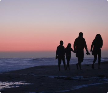 Family walking on the beach with a beautiful sunset in the background