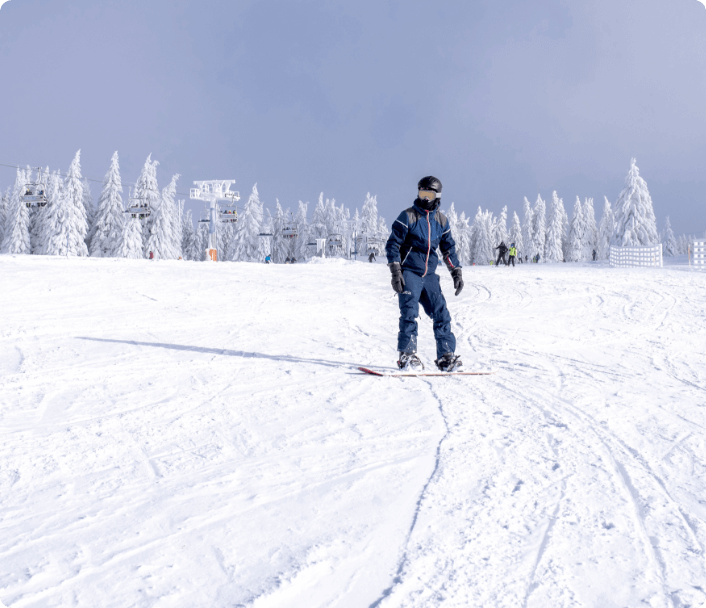 Male snowboarder riding down slope with beautiful winter landscape